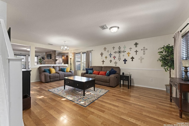 living room with a textured ceiling, an inviting chandelier, a healthy amount of sunlight, and hardwood / wood-style flooring