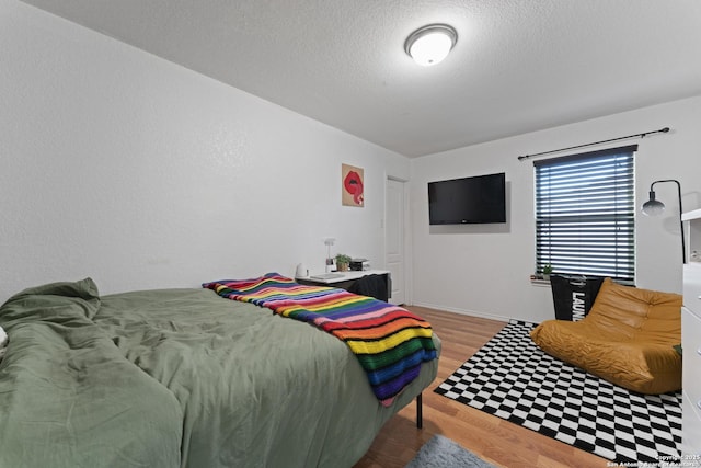 bedroom with a textured ceiling and hardwood / wood-style flooring