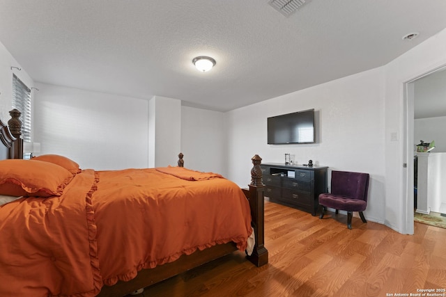 bedroom with a textured ceiling and light hardwood / wood-style flooring