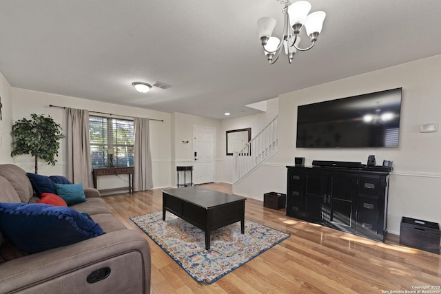 living room with hardwood / wood-style floors, a textured ceiling, and an inviting chandelier