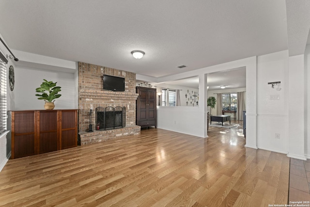 unfurnished living room with a textured ceiling, a fireplace, and light hardwood / wood-style flooring