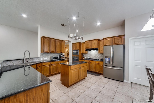 kitchen featuring light tile patterned flooring, a kitchen island, appliances with stainless steel finishes, sink, and decorative backsplash