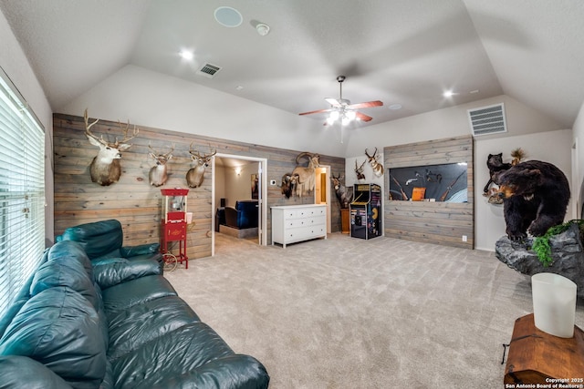 living room with lofted ceiling, light colored carpet, ceiling fan, and wood walls