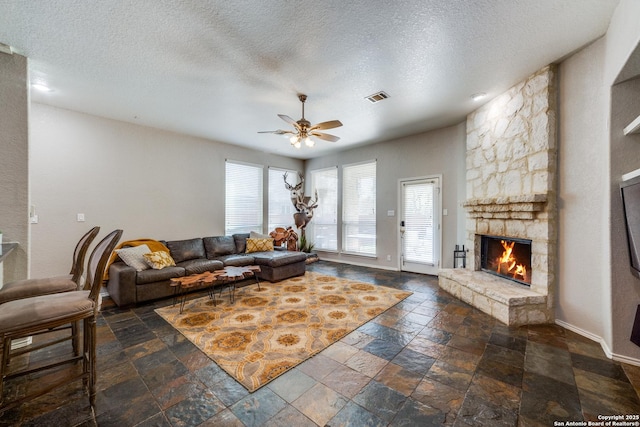 living room featuring a textured ceiling, a fireplace, and ceiling fan