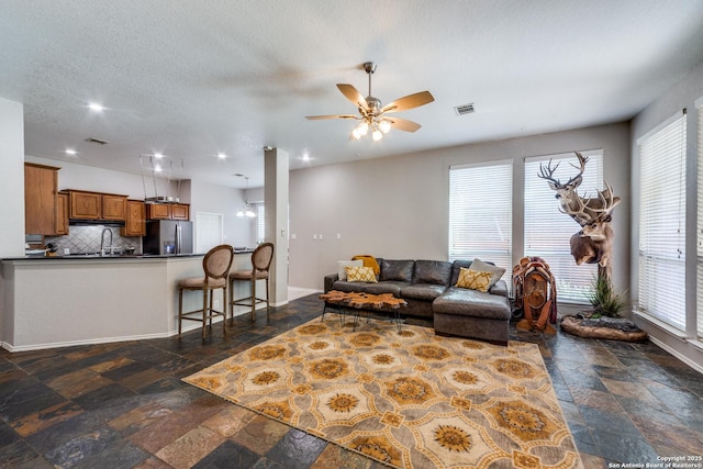 living room featuring sink, a textured ceiling, and ceiling fan