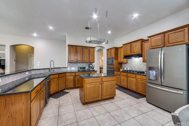 kitchen featuring sink, light tile patterned floors, stainless steel appliances, tasteful backsplash, and a kitchen island