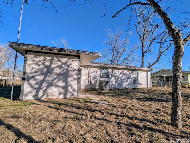 back of house with central AC and a lawn