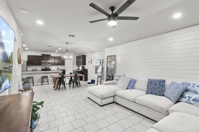 living room with light tile patterned flooring and ceiling fan with notable chandelier