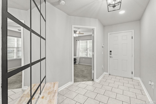 entryway featuring ceiling fan, light colored carpet, and a textured ceiling