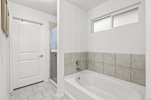 bathroom with a textured ceiling, tile patterned floors, and separate shower and tub