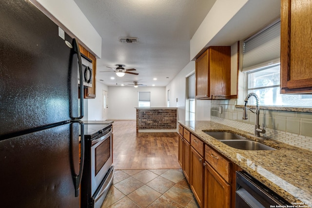 kitchen featuring light tile patterned floors, ceiling fan, light stone countertops, black appliances, and sink