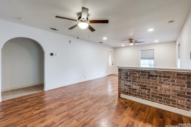 unfurnished living room with a textured ceiling, ceiling fan, and hardwood / wood-style flooring