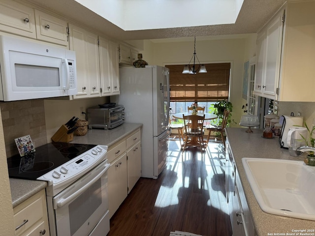 kitchen featuring white cabinetry, white appliances, hanging light fixtures, a chandelier, and sink