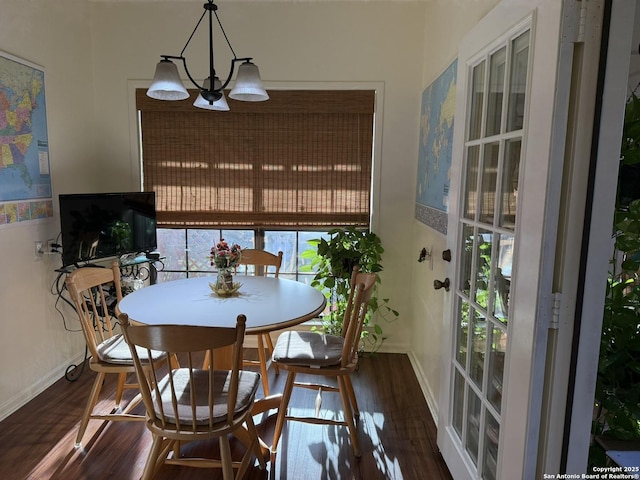 dining space featuring dark wood-type flooring, a wealth of natural light, and an inviting chandelier