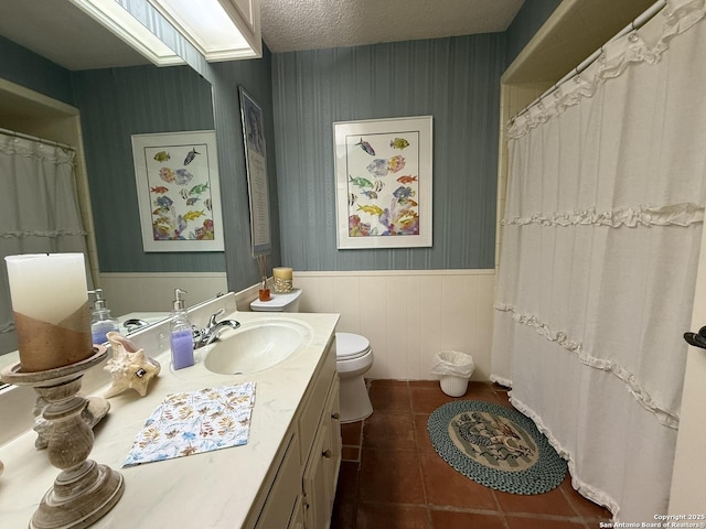 bathroom with a textured ceiling, toilet, tile patterned flooring, and vanity