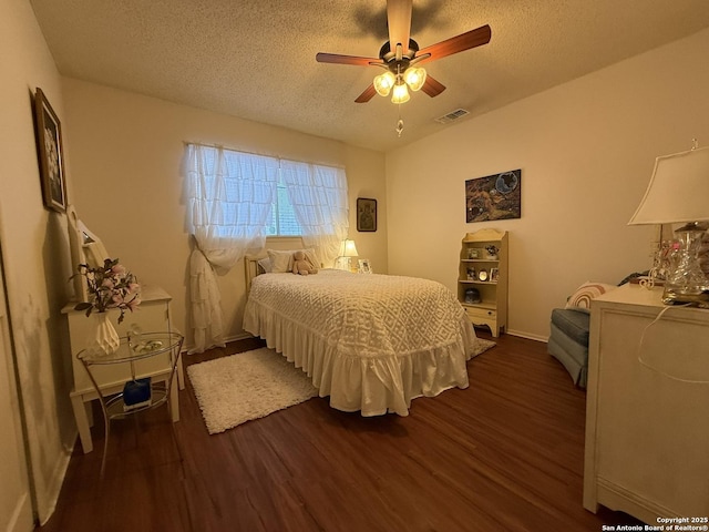 bedroom with ceiling fan, dark wood-type flooring, and a textured ceiling