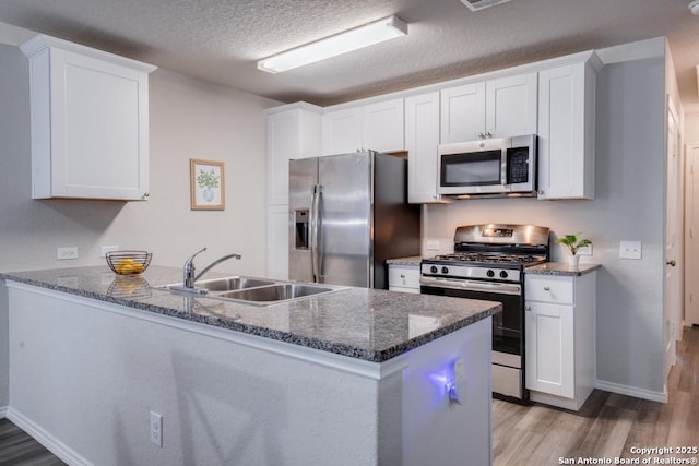 kitchen with white cabinetry, kitchen peninsula, appliances with stainless steel finishes, a textured ceiling, and sink