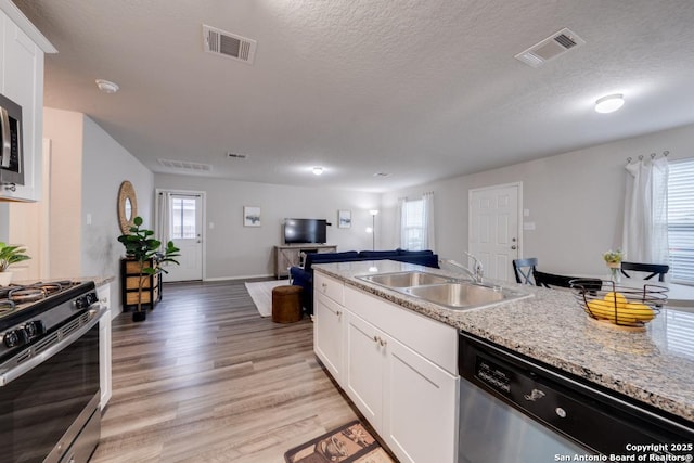 kitchen featuring sink, white cabinetry, light wood-type flooring, a textured ceiling, and stainless steel appliances