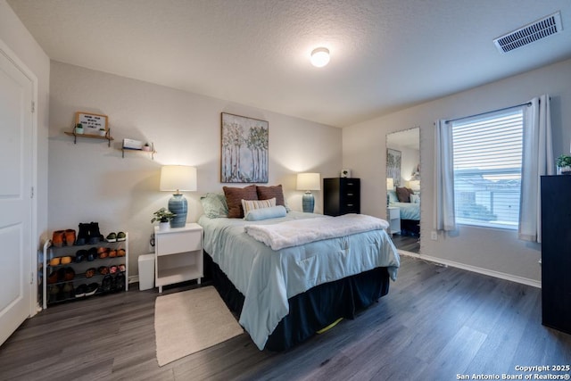 bedroom featuring a textured ceiling and dark hardwood / wood-style flooring