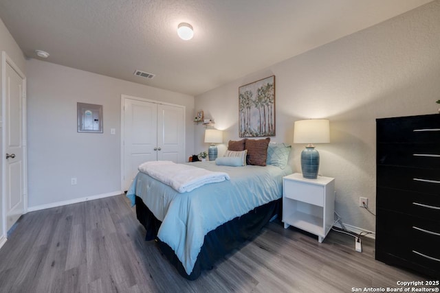 bedroom featuring hardwood / wood-style flooring, a textured ceiling, and a closet