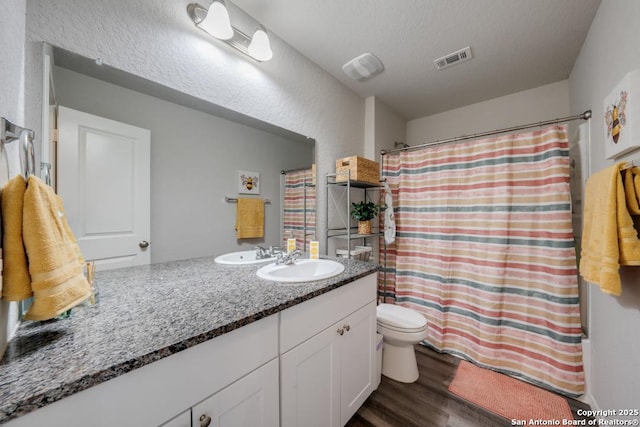 bathroom with toilet, wood-type flooring, walk in shower, a textured ceiling, and vanity