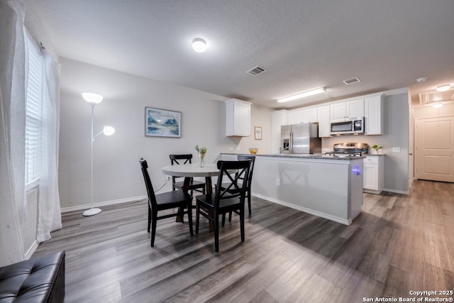 dining space featuring wood-type flooring and a textured ceiling