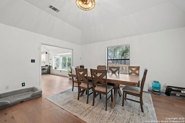 dining space with wood-type flooring and vaulted ceiling