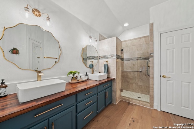 bathroom with walk in shower, vanity, hardwood / wood-style flooring, and lofted ceiling