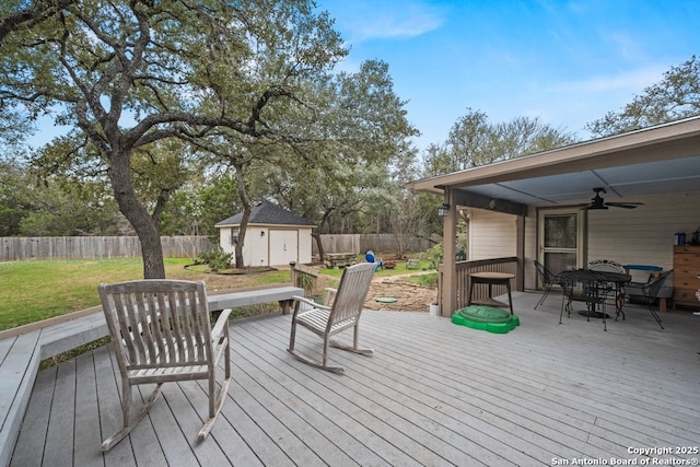 wooden terrace featuring ceiling fan, a storage shed, and a lawn