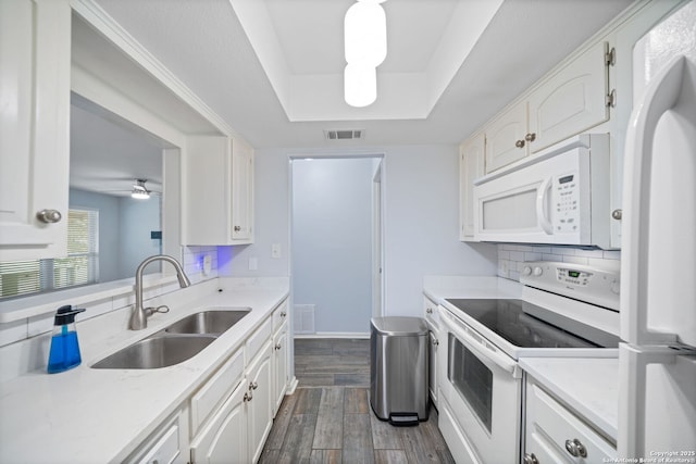 kitchen featuring ceiling fan, sink, a tray ceiling, white appliances, and white cabinetry