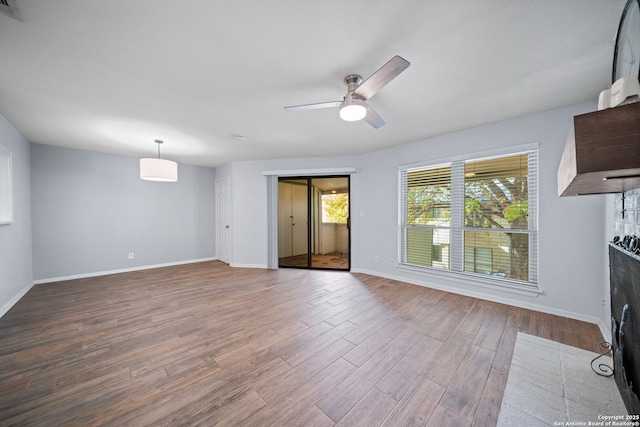 unfurnished living room featuring ceiling fan, wood-type flooring, and a brick fireplace