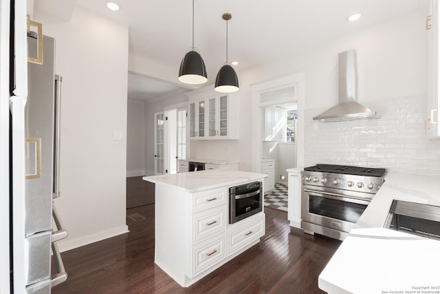 kitchen with white cabinets, wall chimney exhaust hood, high quality appliances, and pendant lighting