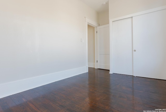 unfurnished bedroom with a closet and dark wood-type flooring