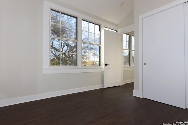 empty room with vaulted ceiling and dark wood-type flooring