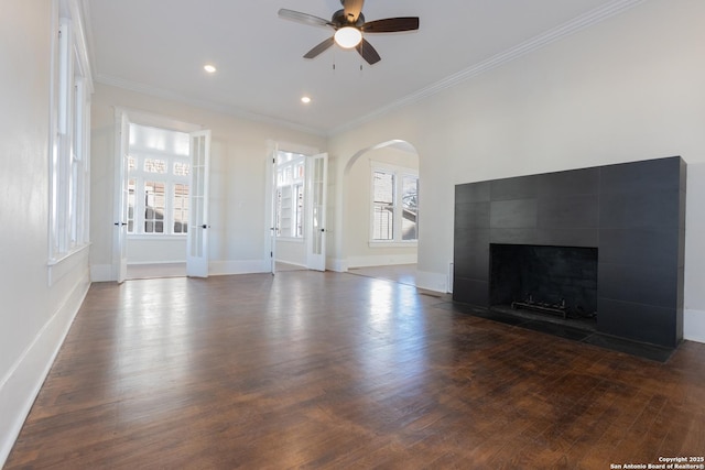 unfurnished living room with ceiling fan, a fireplace, dark hardwood / wood-style flooring, and crown molding