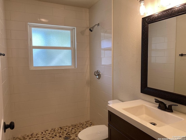 bathroom with toilet, vanity, and a tile shower