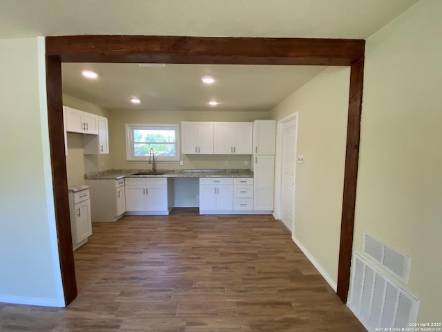 kitchen featuring light stone countertops, sink, white cabinets, and dark hardwood / wood-style floors