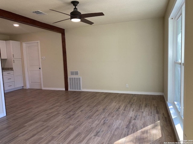 unfurnished living room featuring ceiling fan, beam ceiling, and dark hardwood / wood-style flooring