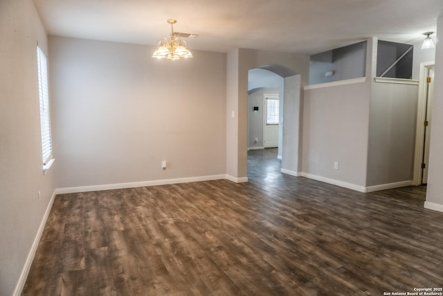 spare room featuring dark hardwood / wood-style floors and a chandelier