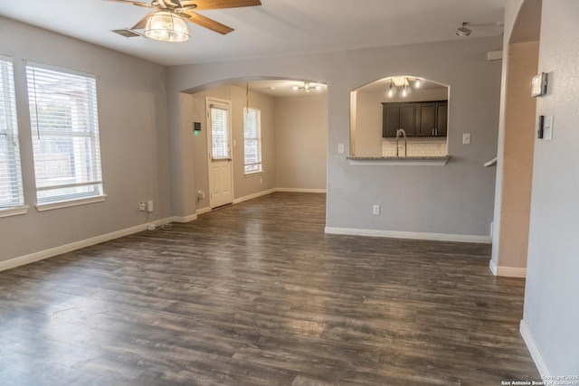 unfurnished living room featuring ceiling fan and dark wood-type flooring