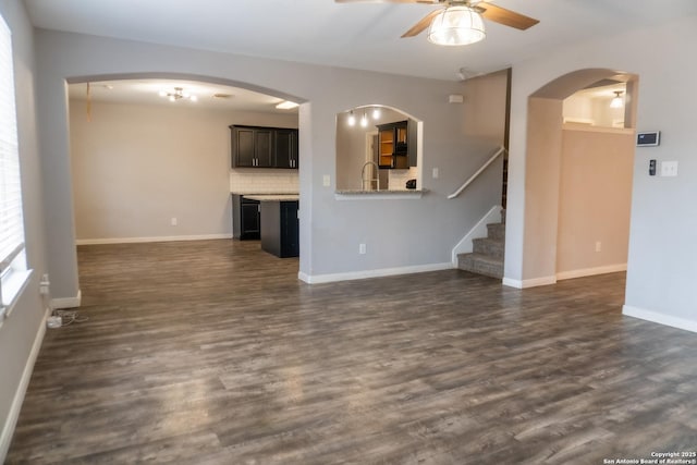 unfurnished living room with dark wood-type flooring, ceiling fan, and sink