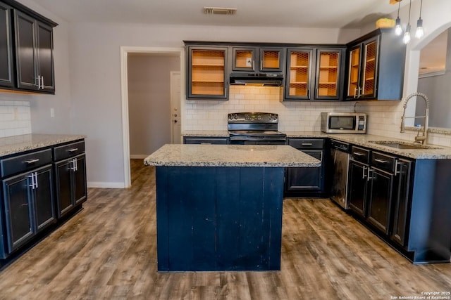 kitchen featuring pendant lighting, stainless steel appliances, tasteful backsplash, sink, and light stone counters