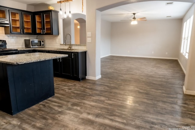 kitchen with ceiling fan, decorative backsplash, dark wood-type flooring, light stone countertops, and sink