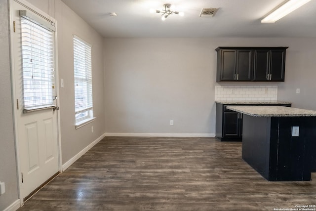 kitchen with light stone countertops, dark wood-type flooring, and tasteful backsplash