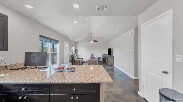 kitchen with ceiling fan, lofted ceiling, and light stone countertops