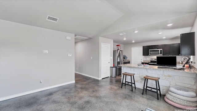 kitchen with light stone countertops, appliances with stainless steel finishes, lofted ceiling, a kitchen breakfast bar, and kitchen peninsula