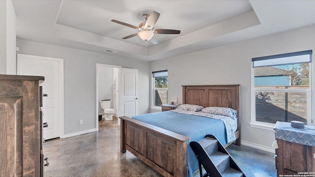 bedroom with ensuite bathroom, ceiling fan, and a tray ceiling