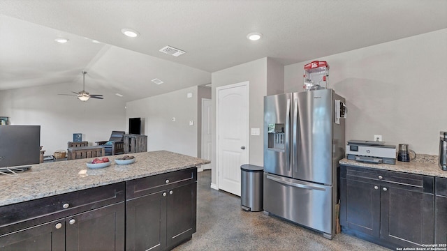 kitchen featuring stainless steel fridge, ceiling fan, a textured ceiling, light stone countertops, and vaulted ceiling