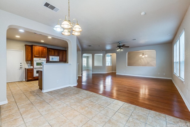 kitchen with ceiling fan with notable chandelier, white appliances, a wealth of natural light, and hanging light fixtures