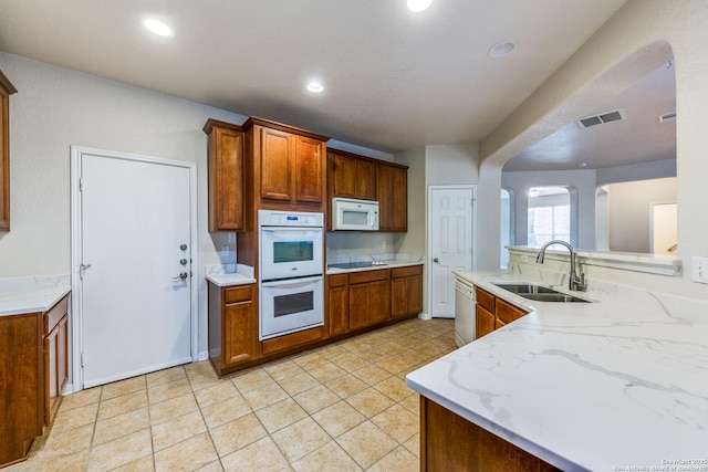 kitchen with light stone counters, sink, and white appliances